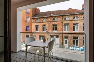 a table and chairs on a balcony with a large window at Bonrepo Room 102 in Bruges