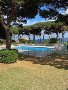une piscine avec des arbres et l'océan en arrière-plan dans l'établissement Appartement vue mer, accès privé plage, piscine, à Sainte-Maxime