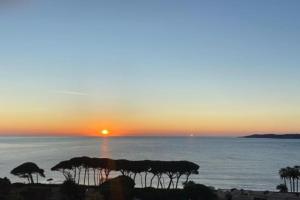 - un coucher de soleil sur l'océan avec des parasols sur une plage dans l'établissement Appartement vue mer, accès privé plage, piscine, à Sainte-Maxime