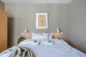 a large white bed with two towels on it at Bonrepo Room 103 in Bruges