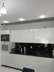 a kitchen with white cabinets and a black counter top at Apartament Zielony Zakątek Wrocław in Wrocław