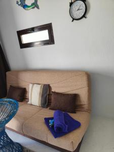 Sofá marrón con almohadas y reloj en la pared en Loft la Caletilla en Caleta de Sebo