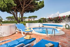 een patio met blauwe stoelen en een zwembad bij Mng Elliott37 in Vale do Lobo