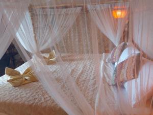 uma cama com cortinas e almofadas brancas em Jungle Bar Honeymoon suite & private pool em San Vicente