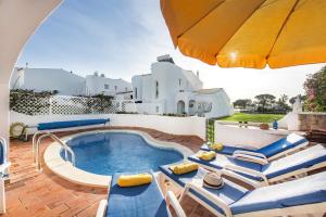 a patio with a pool and chairs and an umbrella at Mng Elliott42 in Vale do Lobo
