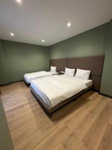a bedroom with two beds with white sheets and wooden floors at Heaven Inn Airport Hotel in Arnavutköy