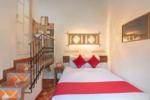 Un dormitorio con una cama con almohadas rojas y una escalera en OYO Hotel Coyopolan en Xico