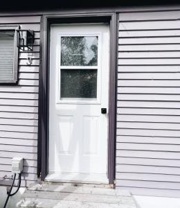 a white door with a window on a house at Cottage Feels in the City - Downtown Apartment & Backyard Bliss in Fredericton