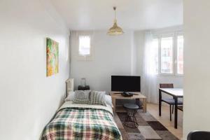 a bedroom with a bed and a desk with a television at Charmant appartement pour 3 personnes à Bagneux in Bagneux