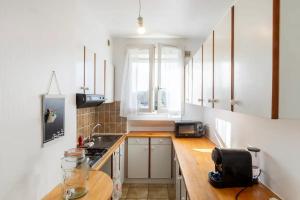 a kitchen with white cabinets and a wooden counter top at Charmant appartement pour 3 personnes à Bagneux in Bagneux