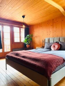 ein Schlafzimmer mit einem großen Bett und einer Holzdecke in der Unterkunft Lovely & great equipped wooden Alp Chalet flat in Kandersteg