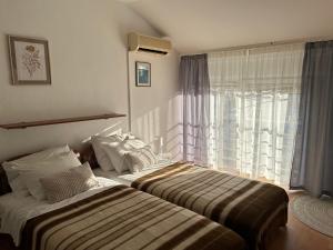 two beds in a hotel room with a window at Pension Rušev in Preko