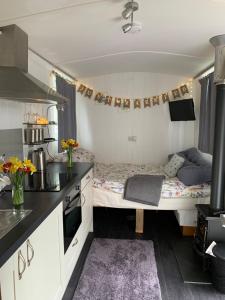 a small kitchen with a bed in a room at Tides Reach, Deluxe Shepherds hut, 100m from the Beach in St Merryn