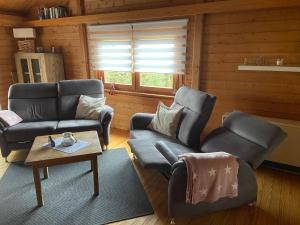 a living room with two chairs and a couch and a table at Blockhaus FerienZauber III in Bromskirchen