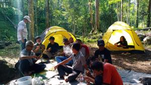 a group of people sitting in front of tents at Joben Evergreen Camp in Tetebatu