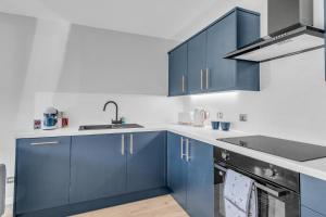 a kitchen with blue cabinets and a sink at King Street Stay - SJA Stays - Luxury 2 Bed Apartment in Aberdeen