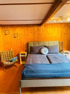 1 dormitorio con 1 cama grande y 1 silla en Lovely & great equipped wooden Alp Chalet flat, en Kandersteg