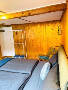 Bett in einem Zimmer mit einer Holzwand in der Unterkunft Lovely & great equipped wooden Alp Chalet flat in Kandersteg