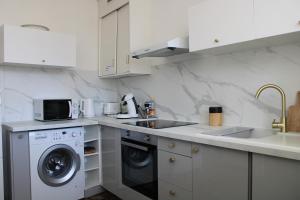 a white kitchen with a washing machine and a sink at Superbe appartement avec parking sur place in Nîmes