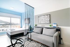 um quarto com uma cama, um sofá e uma janela em Apartamentos próx a UFSC - SVE em Florianópolis