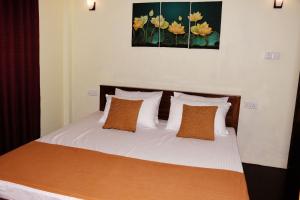 sypialnia z łóżkiem z białą pościelą i pomarańczowymi poduszkami w obiekcie Leaf Dew Resort w mieście Anuradhapura