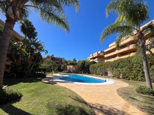 a swimming pool in front of a building with palm trees at Cala Azul Unique in La Cala de Mijas