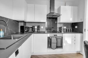 a kitchen with white cabinets and a sink at Urban City Stay - SJA Stays - Luxury 2 Bed Apartment in Aberdeen