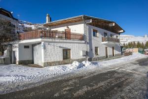 a white building with a balcony on a snowy street at Studio Borgata Ski In Ski Out 300m - Happy Rentals in Sestriere