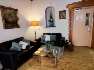 a living room with a black couch and a glass table at HOTEL Schiff in Rastatt