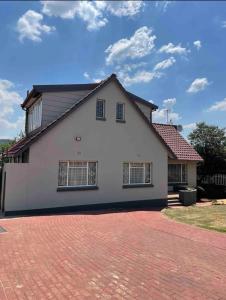 a white house with a red roof and a brick driveway at Downham Views in Johannesburg