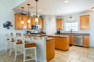 a kitchen with wooden cabinets and a island with bar stools at CR Escape in Dauphin Island