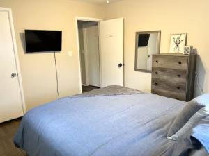 a bedroom with a bed and a dresser and a television at Queen Suite - Hot Tub - Wifi Room 2 in Forest Park