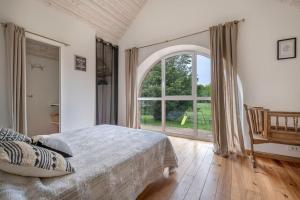 1 dormitorio con cama y ventana grande en Gîte les Arcades 25 couchages, en Saint-Gildas-des-Bois