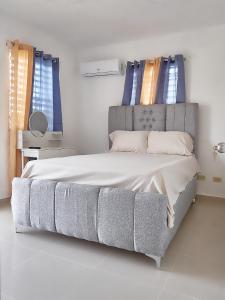 Schlafzimmer mit einem großen Bett und blauen Fenstern in der Unterkunft Lovely and peaceful stay in San Pedro de Macorís