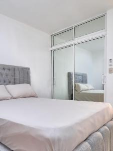 1 dormitorio con 1 cama blanca grande y espejo en Lovely and peaceful stay, en San Pedro de Macorís
