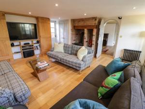 ein Wohnzimmer mit zwei Sofas und einem Fernseher in der Unterkunft Home Farm Cottage in Southam