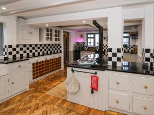 a kitchen with white cabinets and black counter tops at Home Farm Cottage in Southam