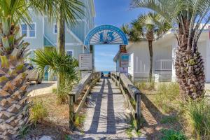 a boardwalk leading to a building with palm trees at Panama City Beach Home Steps to the Ocean! in Panama City Beach