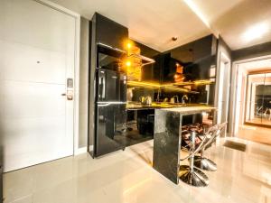 une cuisine avec des armoires noires et un comptoir noir dans l'établissement Grand Sungkono Lagoon Apartment 2BR Surabaya by Le Ciel Hospitality, à Surabaya