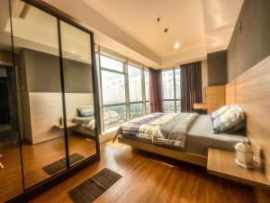 a bedroom with a bed and a large window at Grand Sungkono Lagoon Apartment 2BR Surabaya by Le Ciel Hospitality in Surabaya