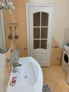a bathroom with a sink and a washing machine at Bedroom + Living Large Apartment 75m2 in Chişinău