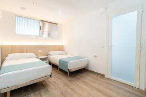 2 Betten in einem Zimmer mit weißen Wänden und Holzböden in der Unterkunft New Kensington Apartments - Econotels in Magaluf