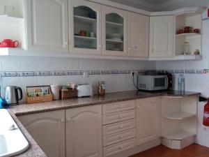 a kitchen with white cabinets and a microwave at Hakuna Matata Hostel in Zambujeira do Mar