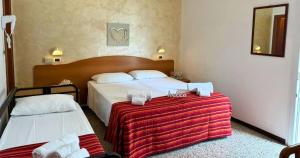 una camera d'albergo con due letti e una coperta rossa di Hotel Caruso a Rimini