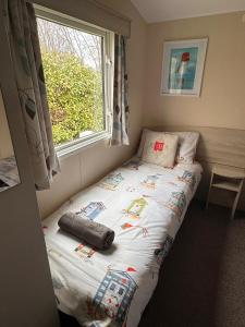 een bed in een kleine kamer met een raam bij Fabulous Modern Holiday Home BEACH Cleethorpes Beach Thorpe Park Haven in Cleethorpes