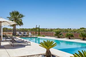 a swimming pool with chaise lounge chairs and an umbrella at Villa Es Trenc in Campos