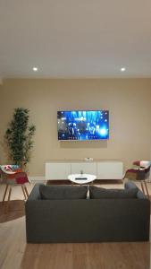 sala de estar con sofá y TV en la pared en Apartamento Pumarin, en Oviedo