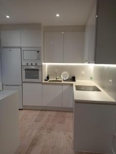 una cocina blanca con armarios blancos y fregadero en Apartamento Pumarin, en Oviedo