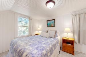 1 dormitorio con 1 cama, 2 lámparas y ventana en Captain John's Cannon Beach, en Cannon Beach