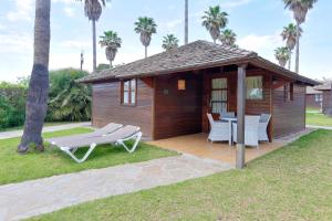 a small cabin with a table and chairs and palm trees at Camping & Resort Sangulí Salou in Salou